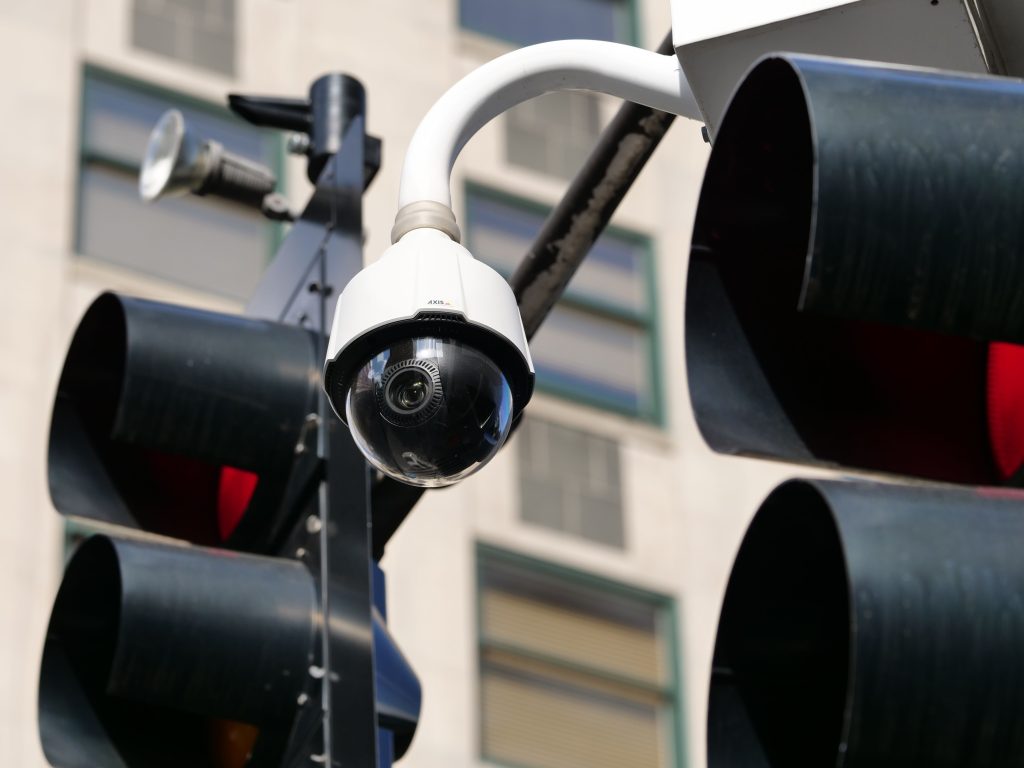 Close-up of a modern dome security camera monitoring an urban street.